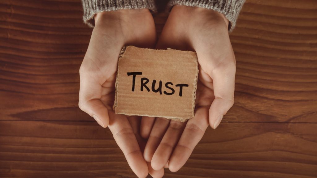 hands holding a card reading 'trust'