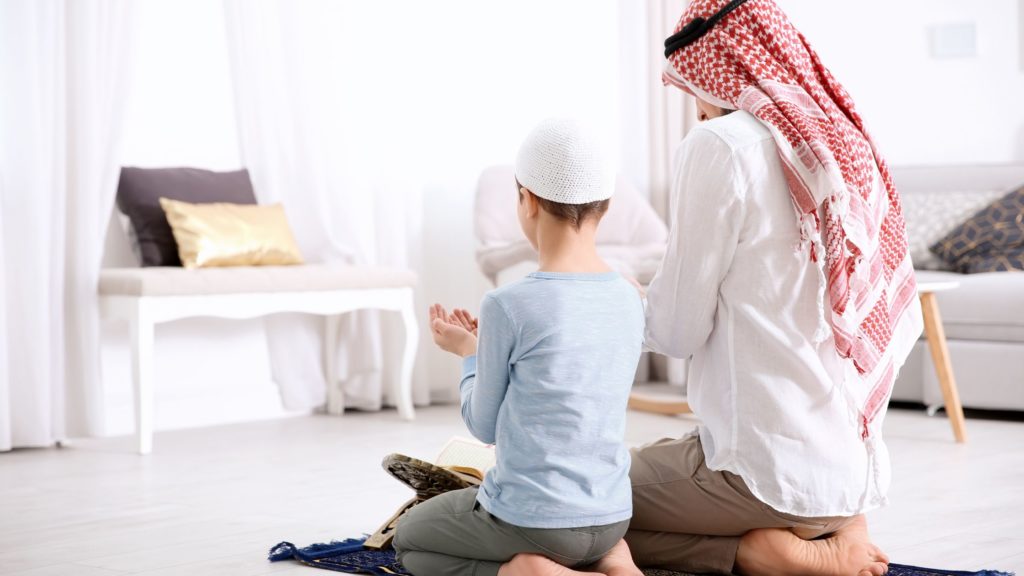 man and boy praying together in a white home