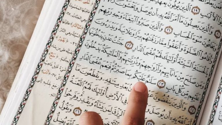 a finger on the Qur'an (to direct the eyes to one line)